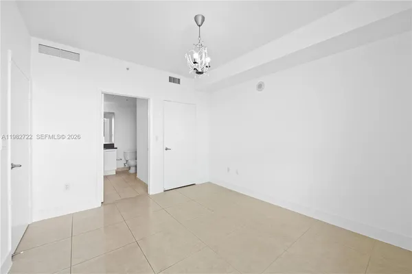 an empty room with a chandelier fan and windows