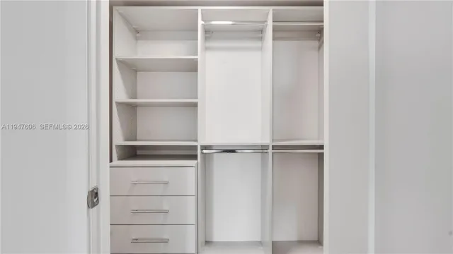 a view of empty walk in closet with wooden floor