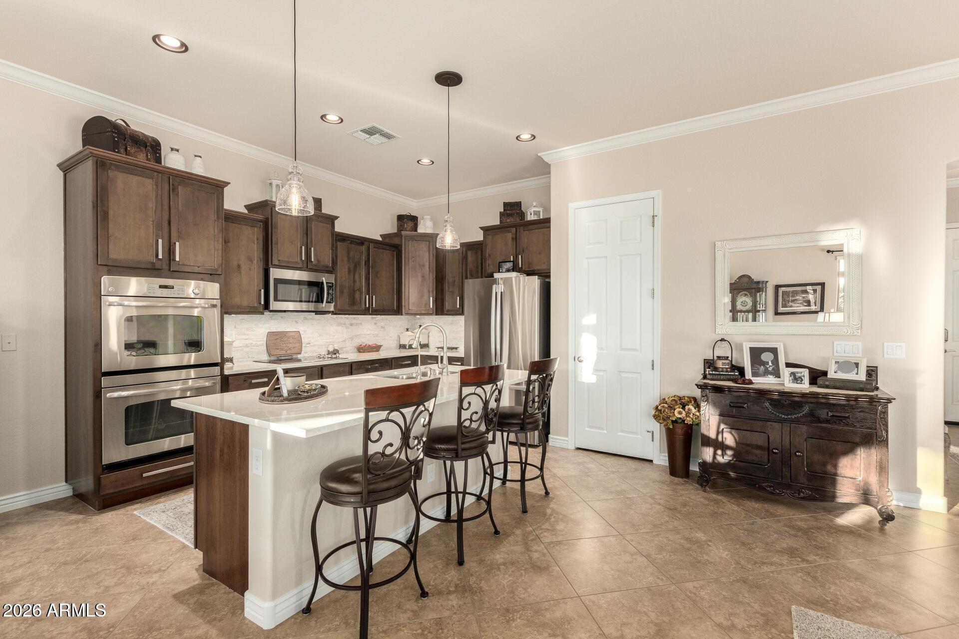 17869 West Verdin Road Goodyear, AZ 85338 - Photo 6 of 39 a kitchen with stainless steel appliances kitchen island granite countertop a stove refrigerator and cabinets