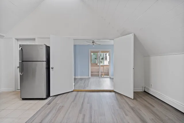 a view of empty room with wooden floor and refrigerator