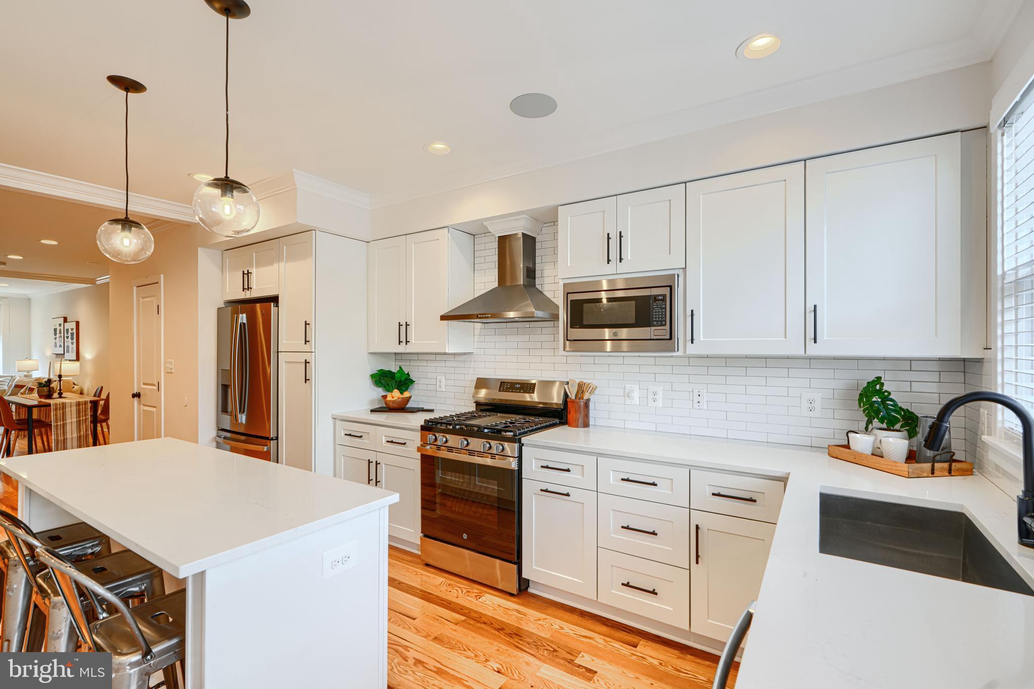814 Grundy Street Baltimore, MD 21224 - Photo 12 of 31 a kitchen with stainless steel appliances white cabinets a sink a stove a refrigerator and island with wooden floor