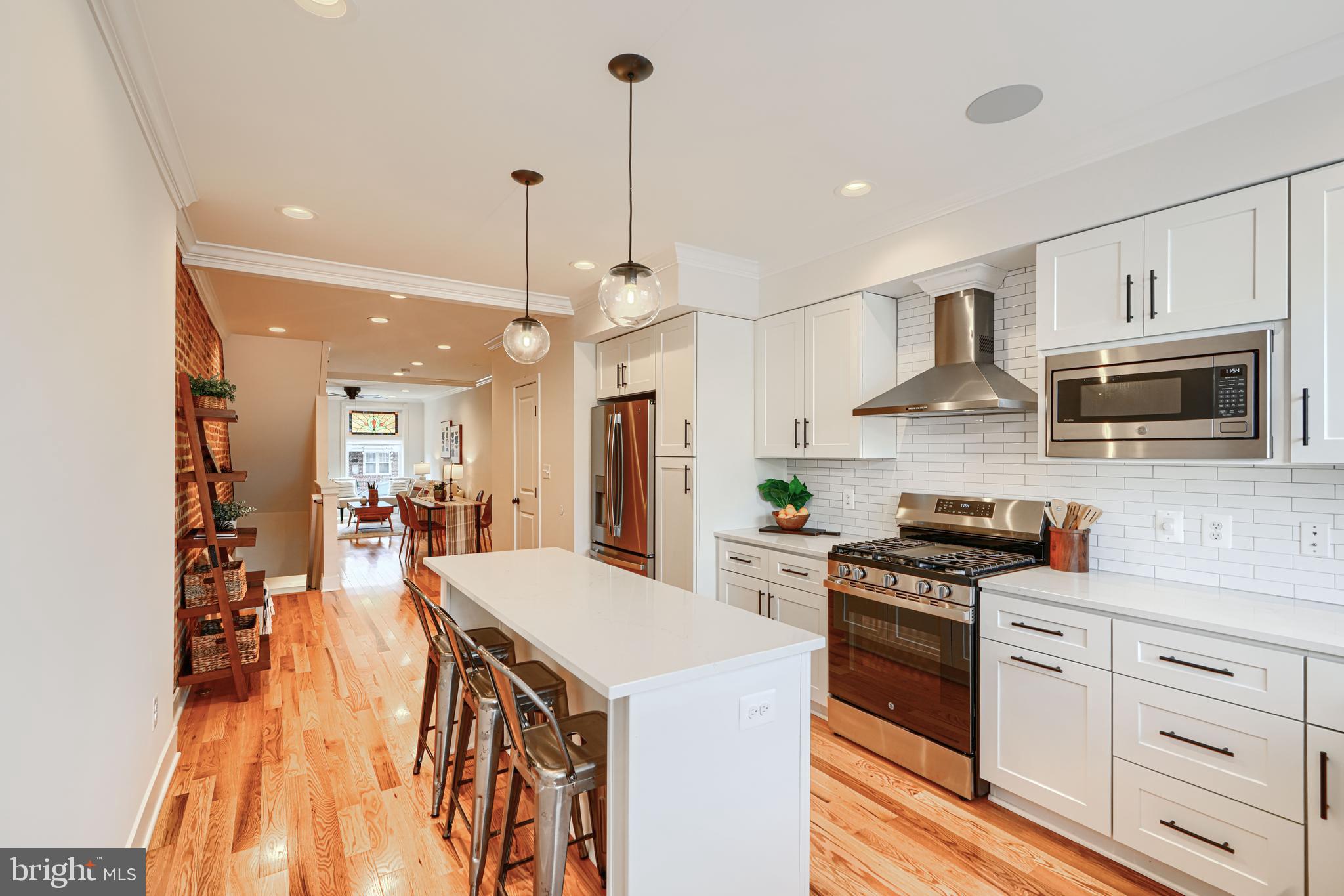 814 Grundy Street Baltimore, MD 21224 - Photo 13 of 31 a large kitchen with kitchen island a stove a sink a refrigerator and a wooden floor