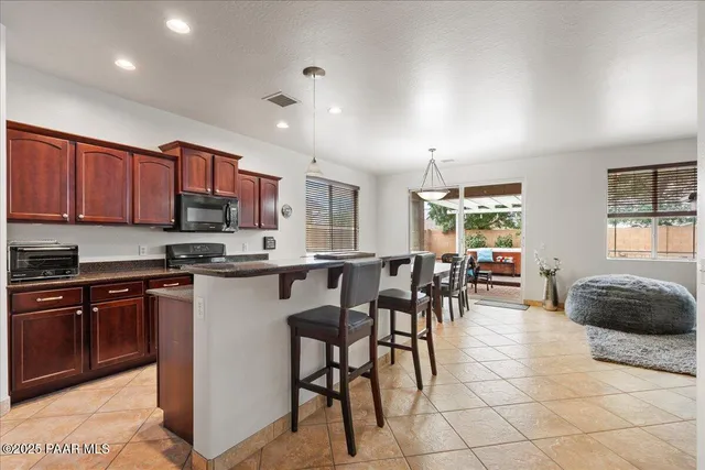 a kitchen with stainless steel appliances granite countertop a stove a sink a dining table and chairs
