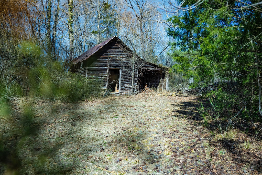 900 Asaville School Road Anderson, SC 29621 - Photo 11 of 29 This rustic barn, nestled amidst verdant trees, offers a charming rural backdrop.
