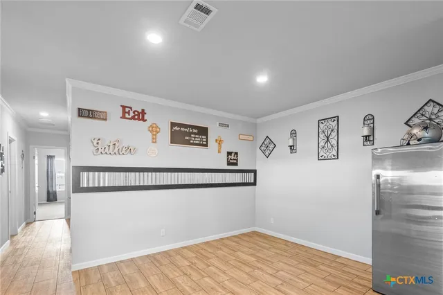 a view of a refrigerator in kitchen and an empty room