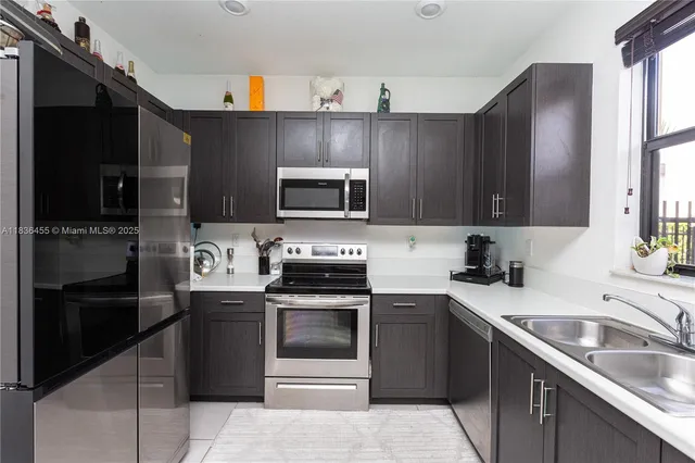 a kitchen with granite countertop a sink dishwasher stove and refrigerator with wooden floor