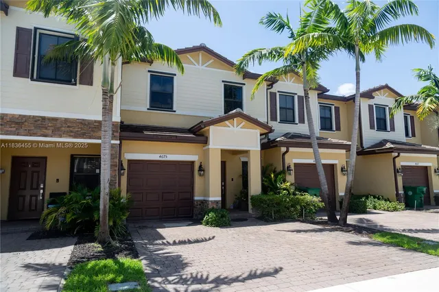 a front view of a house with a yard and potted plants