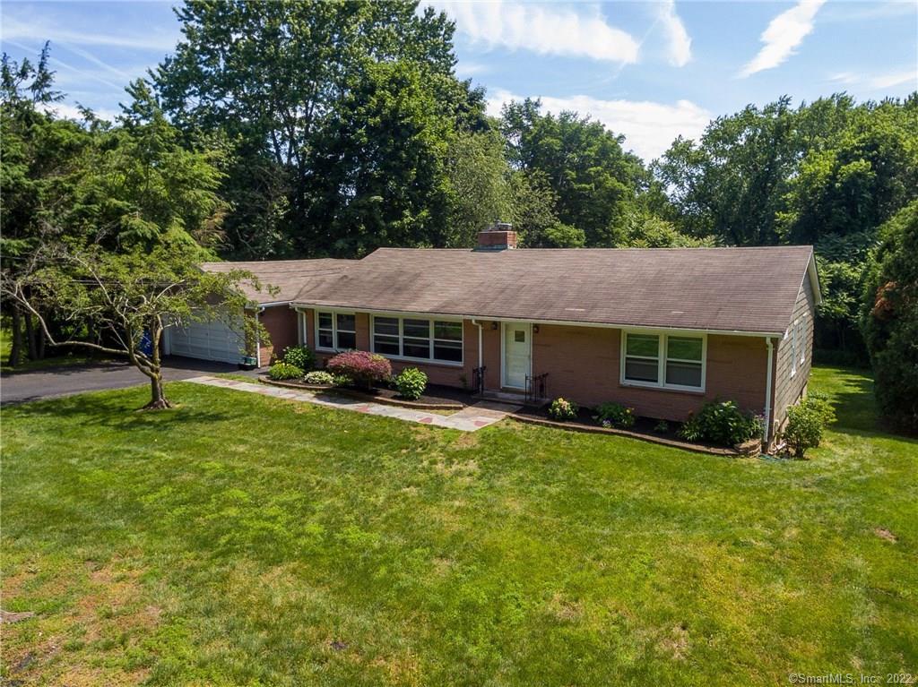 a front view of a house with a garden and trees