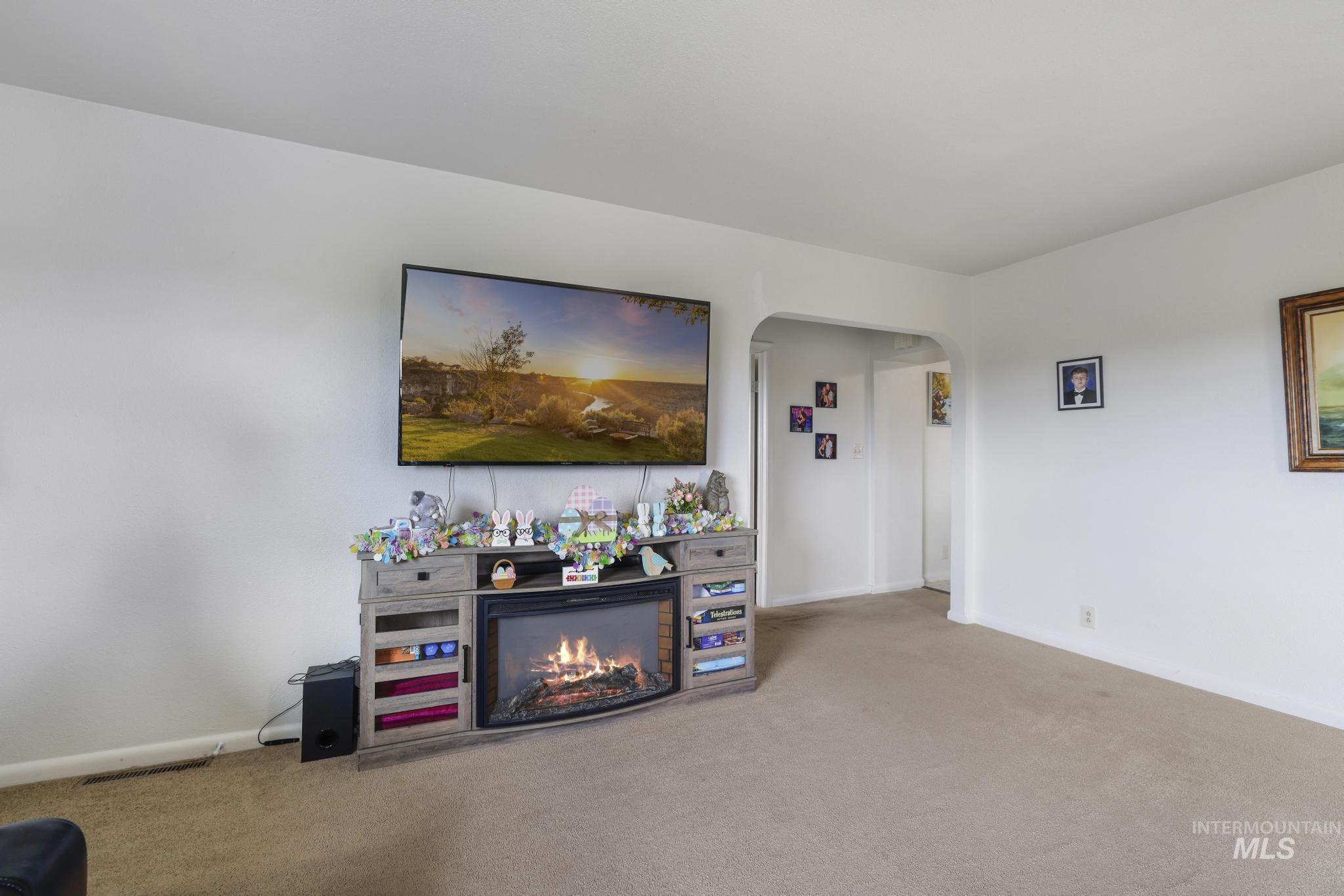 88 South 400 Road West Jerome, ID 83338 - Photo 11 of 31 Living area with carpet floors, arched walkways, and a lit fireplace