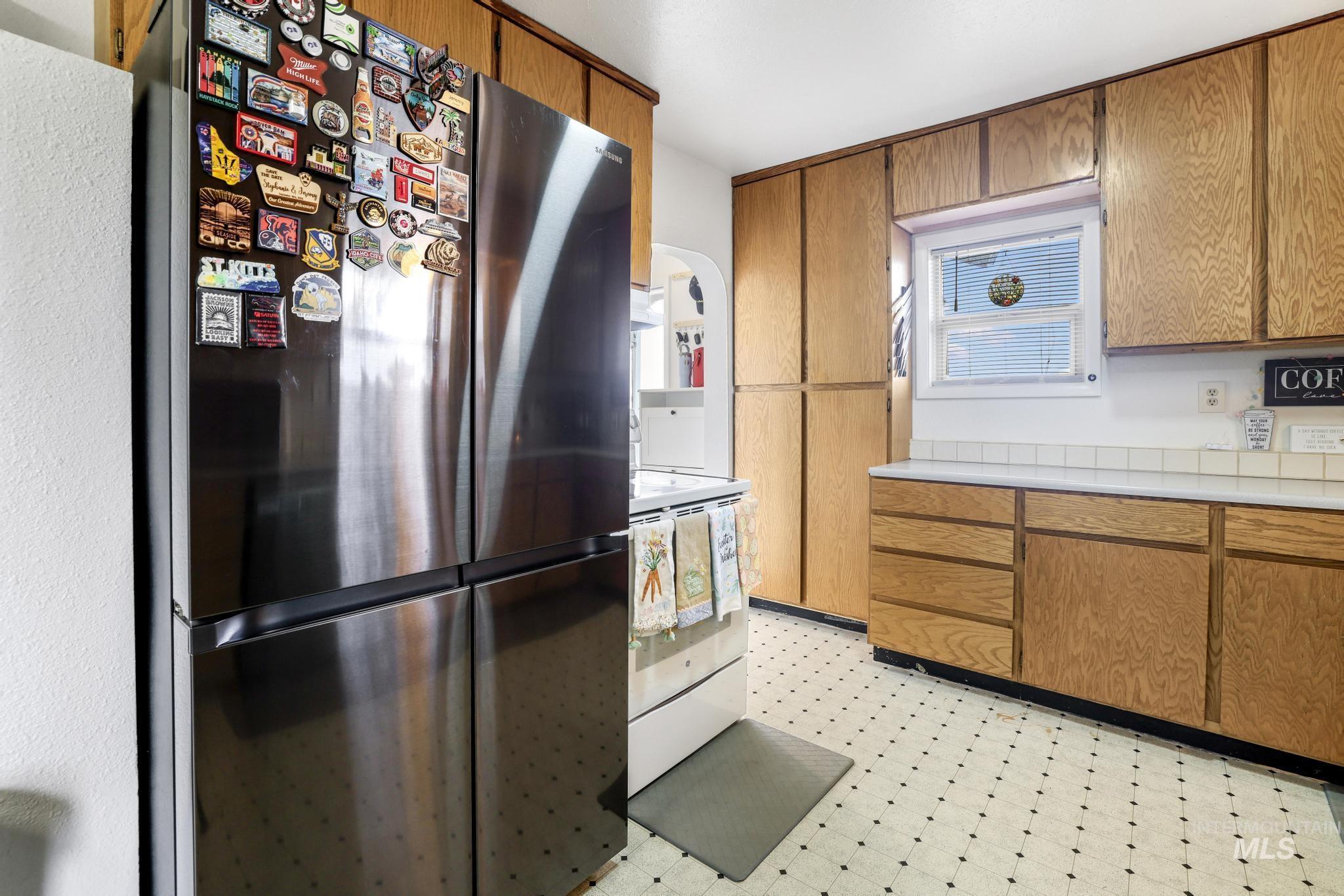 88 South 400 Road West Jerome, ID 83338 - Photo 14 of 31 Kitchen featuring freestanding refrigerator, light floors, wood finish cabinetry, light countertops, and white range with electric cooktop