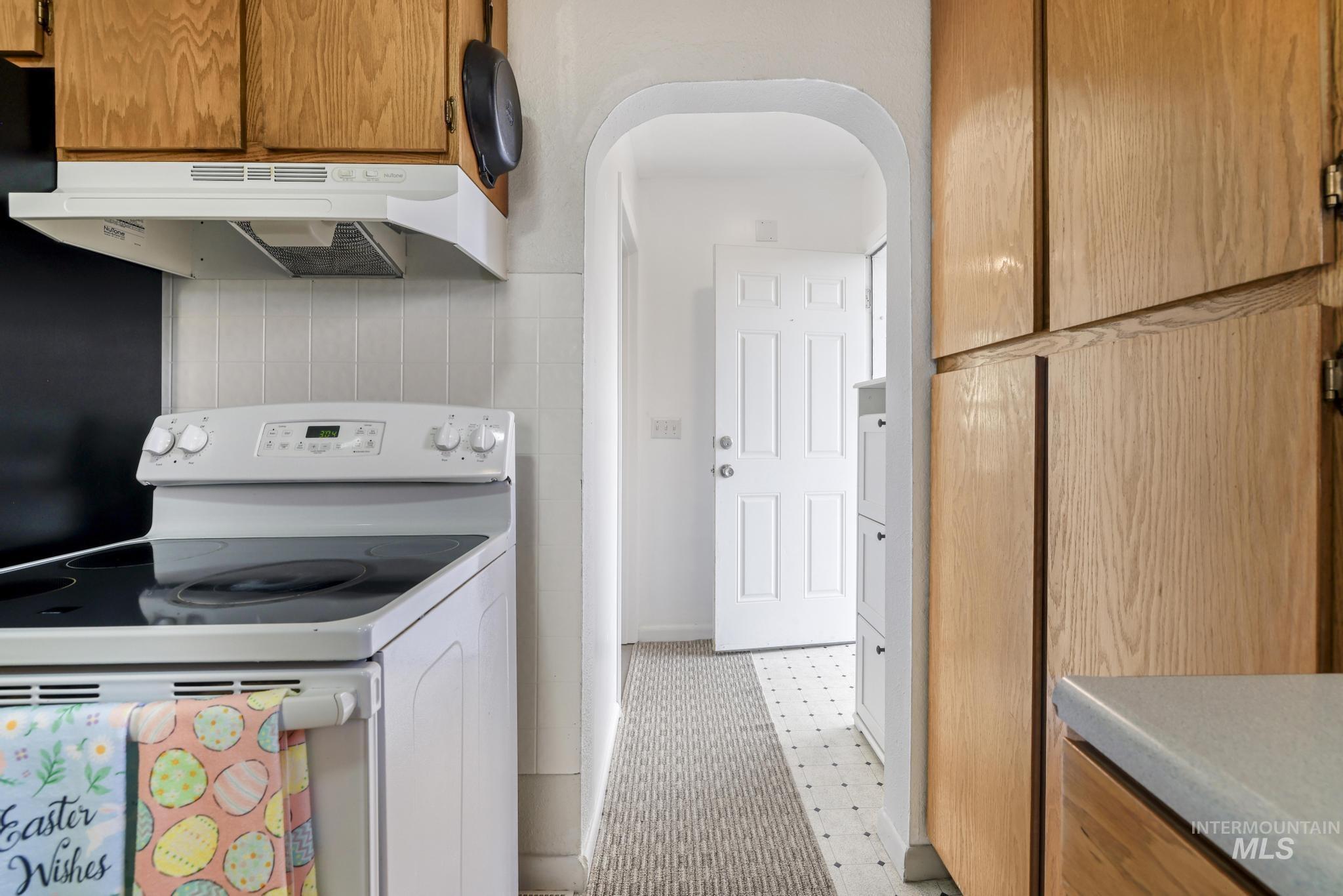 88 South 400 Road West Jerome, ID 83338 - Photo 15 of 31 Kitchen with white range with electric cooktop, wood finish cabinets, arched walkways, light countertops, and light floors