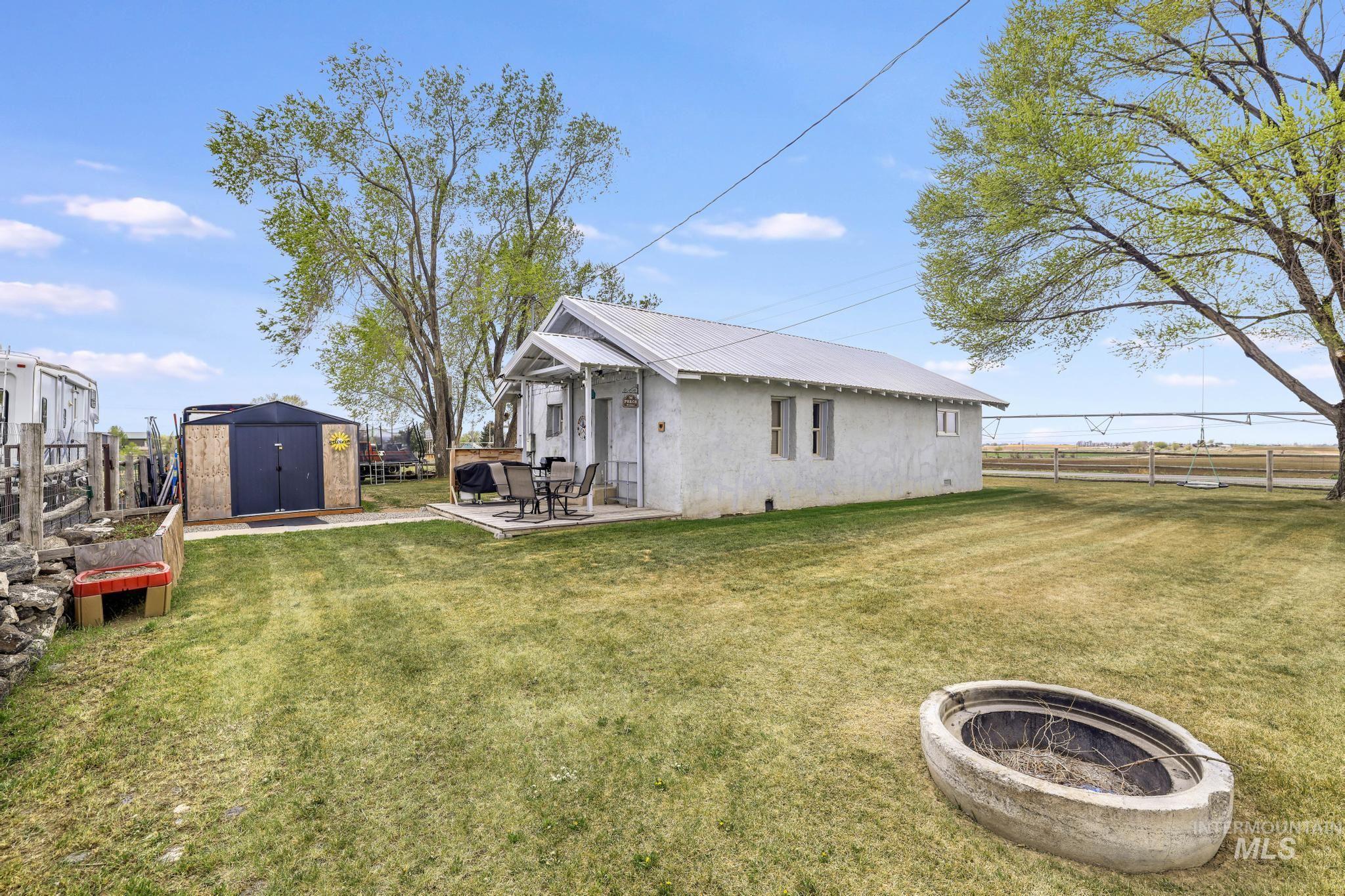 88 South 400 Road West Jerome, ID 83338 - Photo 5 of 31 Rear view of property featuring a storage unit, a fenced backyard, an outdoor fire pit, a patio, and a metal roof