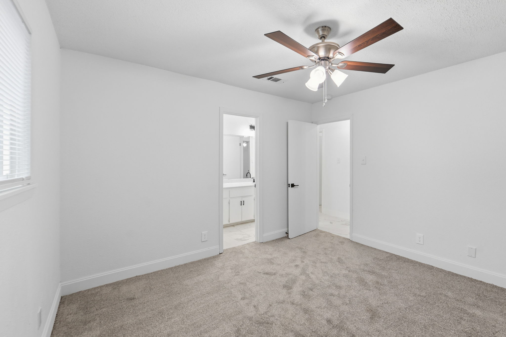 8203 Colony Loop Drive Austin, TX 78724 - Photo 30 of 38 A well-lit bedroom offering plush carpeting and a modern ceiling fan, with convenient access to a private bathroom.