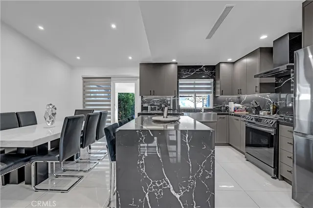 a kitchen with stainless steel appliances granite countertop a stove a refrigerator a sink dishwasher a dining table and chairs with wooden floor