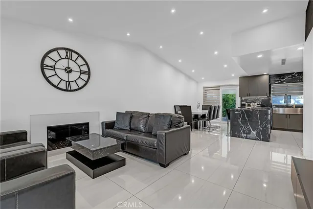 a living room with furniture a clock on wall and a flat screen tv