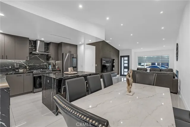 a kitchen with stainless steel appliances granite countertop a stove a sink a refrigerator and chairs