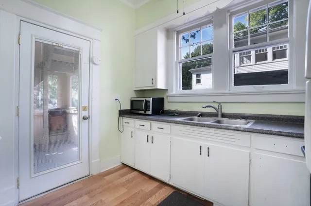 a view of an empty room with wooden floor and a ceiling fan