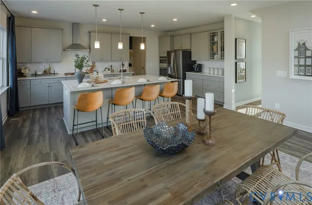 a kitchen with stainless steel appliances kitchen island granite countertop a table chairs sink and cabinets