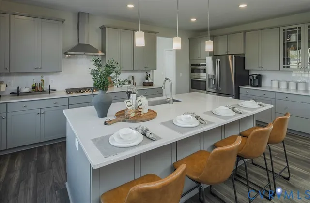 a kitchen with stainless steel appliances kitchen island granite countertop a dining table chairs and a refrigerator
