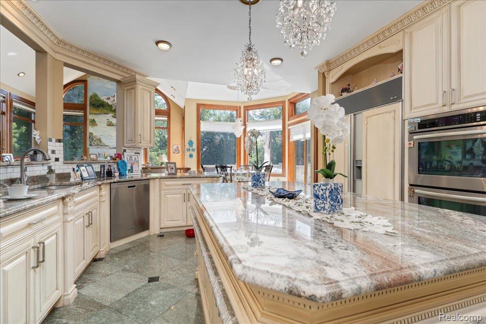 3543 Cedar Brook Drive Rochester, MI 48309 - Photo 15 of 99 Gourmet kitchen featuring a large central island, light-toned cabinetry, stainless steel appliances, and decorative chandeliers