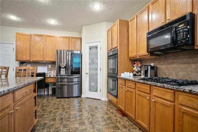 a kitchen with stainless steel appliances a stove a sink a microwave a refrigerator and cabinets