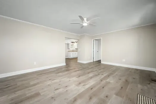 an empty room with wooden floor fan and windows