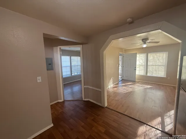 a view of an empty room with a window and wooden floor
