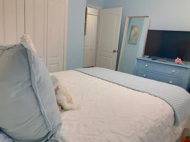 a bedroom with a bed and a flat tv screen on dresser