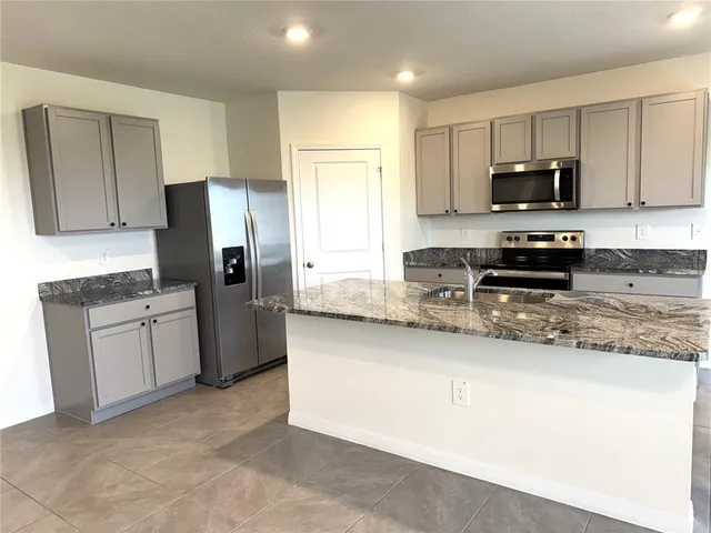 a kitchen with stainless steel appliances granite countertop a stove a sink and a refrigerator