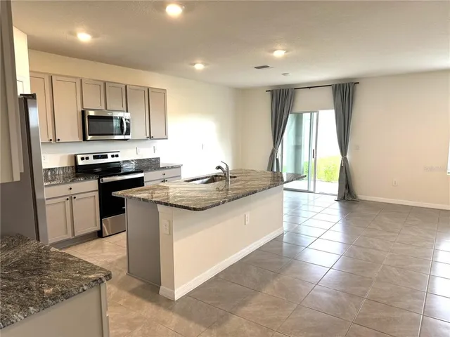 a large white kitchen with a refrigerator a stove top oven and a sink