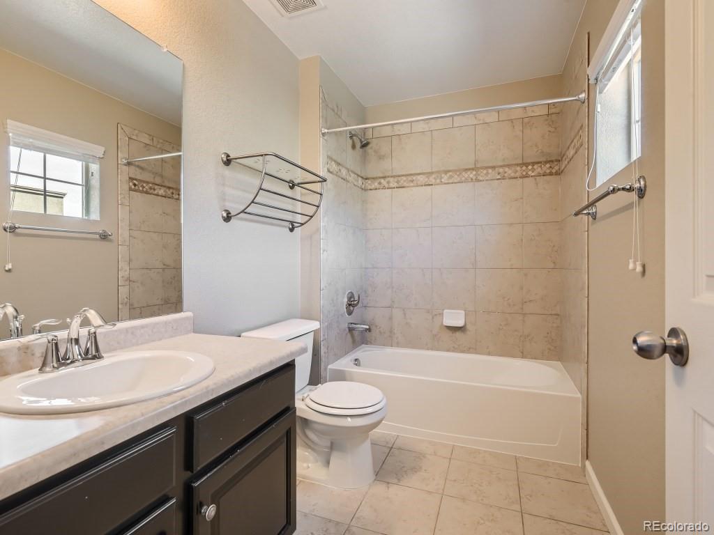 950 Elmhurst Drive, Unit E Highlands Ranch, CO 80129 - Photo 20 of 28 a bathroom with a granite countertop sink a toilet and shower