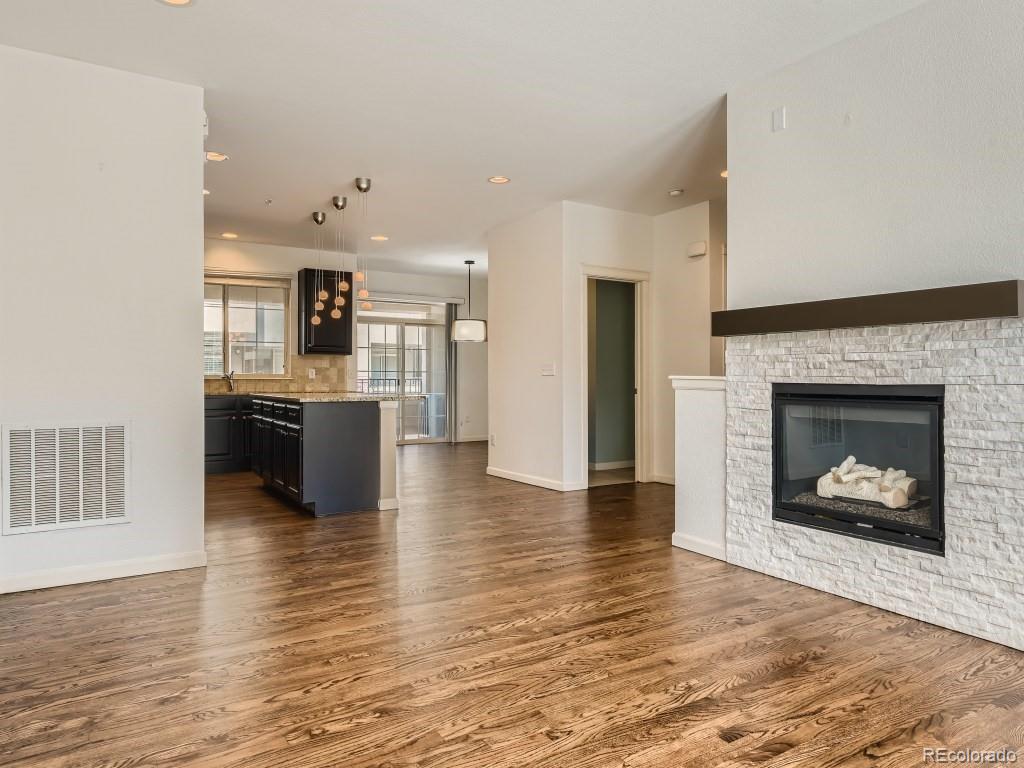 950 Elmhurst Drive, Unit E Highlands Ranch, CO 80129 - Photo 6 of 28 a view of a kitchen and an empty room with wooden floor a fireplace