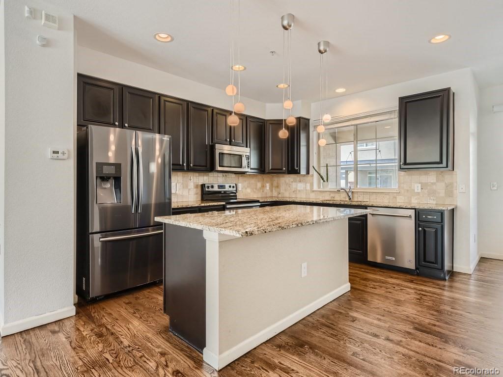 950 Elmhurst Drive, Unit E Highlands Ranch, CO 80129 - Photo 7 of 28 a kitchen with kitchen island stainless steel appliances a sink cabinets and a counter top space