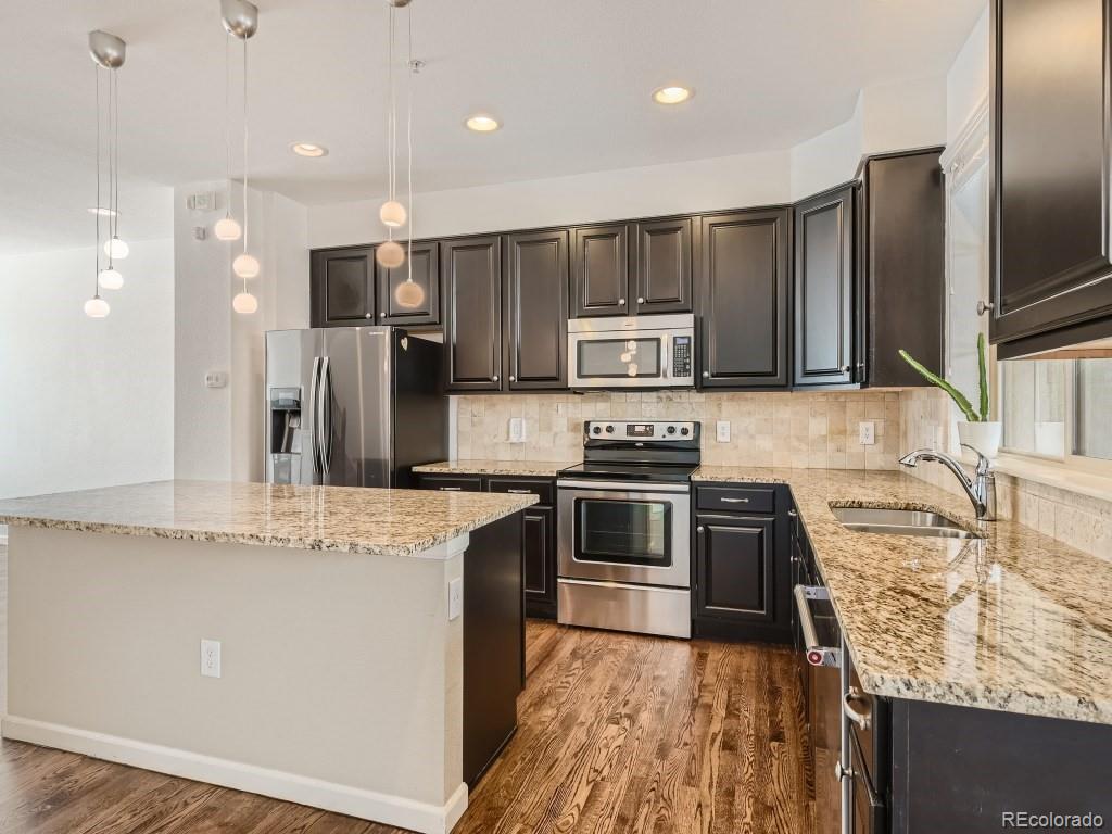950 Elmhurst Drive, Unit E Highlands Ranch, CO 80129 - Photo 9 of 28 a kitchen with kitchen island granite countertop stainless steel appliances and sink