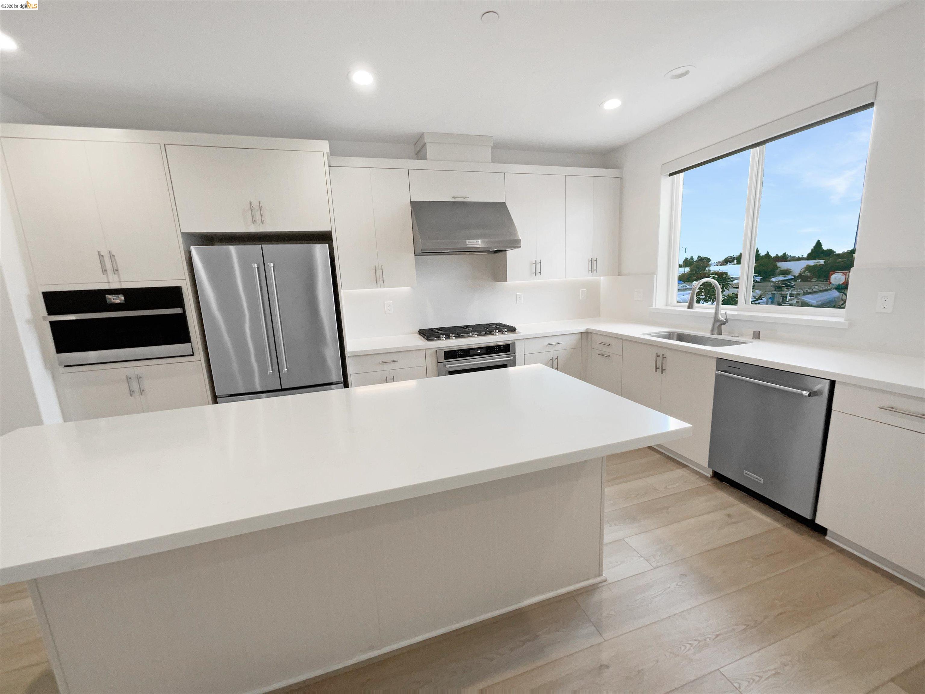 3419 Router Common Fremont, CA 94538 - Photo 13 of 26 Kitchen featuring stainless steel appliances, under cabinet range hood, a center island, recessed lighting, and light wood-style floors