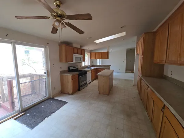 a kitchen with stainless steel appliances granite countertop a refrigerator a sink a stove top oven a counter space and cabinets