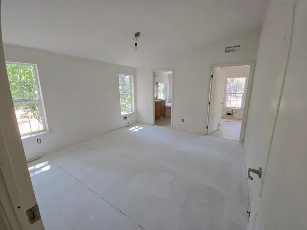 a view of a big room with windows and chandelier fan