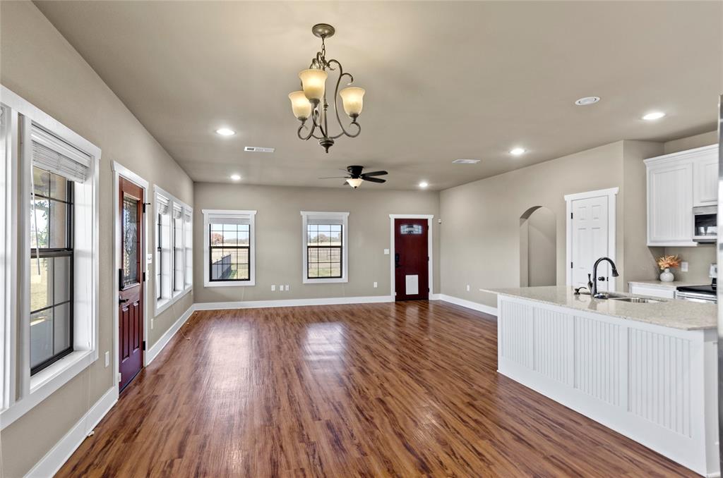 395 Yacht Club Road Oak Point, TX 75068 - Photo 15 of 23 Kitchen with white cabinetry, arched walkways, decorative light fixtures, light stone counters, and recessed lighting