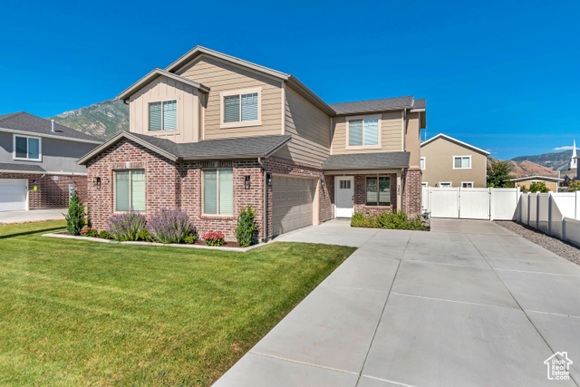 Craftsman-style house featuring a mountain view, board and batten siding, concrete driveway, brick siding, and an attached garage