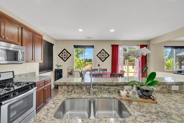 a kitchen with stainless steel appliances granite countertop a stove a sink and a microwave