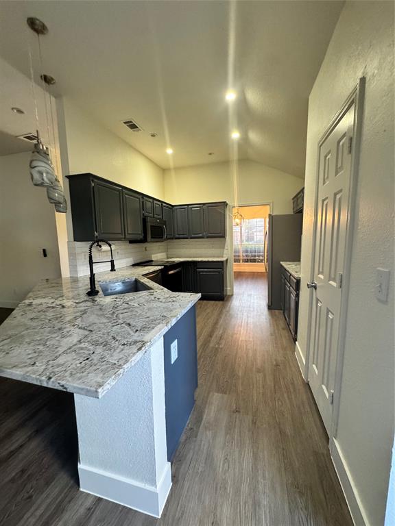 8104 Sebastian Frisco, TX 75035 - Photo 2 of 16 Kitchen featuring vaulted ceiling, decorative backsplash, light stone countertops, pendant lighting, and dark wood-style floors