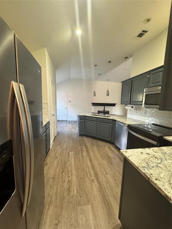 8104 Sebastian Frisco, TX 75035 - Photo 3 of 16 Kitchen with a peninsula, lofted ceiling, fridge, light stone countertops, and stove