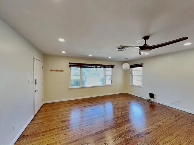 a view of empty room with wooden floor and fan