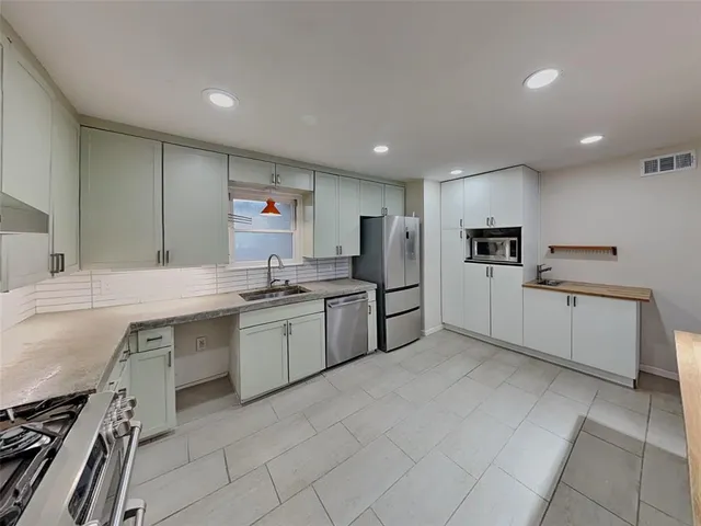 a kitchen with white cabinets a sink stove and refrigerator