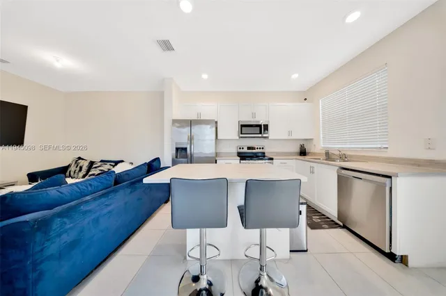 a kitchen with kitchen island granite countertop a sink cabinets and wooden floor