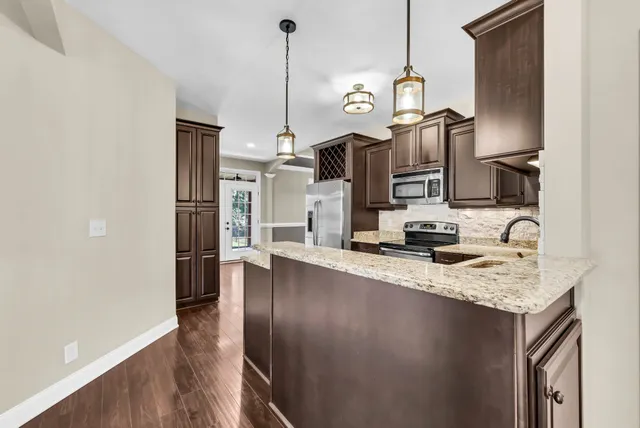 a kitchen with stainless steel appliances granite countertop a sink a refrigerator a stove and a wooden floors
