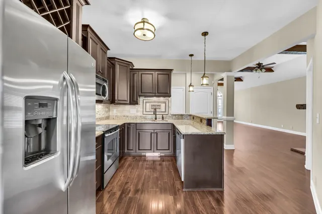 a kitchen with stainless steel appliances granite countertop a refrigerator a stove and a wooden floors