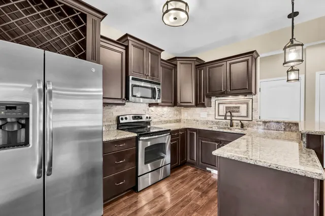 a kitchen with kitchen island granite countertop stainless steel appliances and a refrigerator