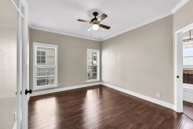 an empty room with wooden floor and a ceiling fan