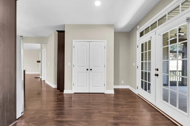 a view of an empty room with wooden floor and windows